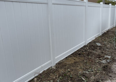 White vinyl privacy fence with tall vertical panels and capped posts