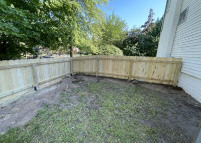 Wooden privacy fence enclosing a small yard area beside a house