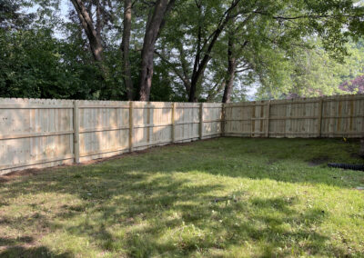 Wooden privacy fence in a grassy yard with trees in the background