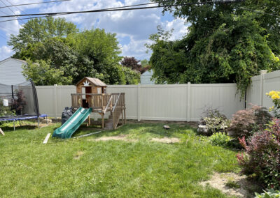 Vinyl fencing enclosing a residential backyard with a playset and trampoline