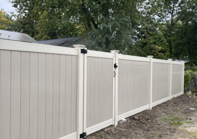 Beige vinyl privacy fence with white posts in a residential area