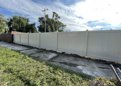 Tall white vinyl privacy fence with a dark wooden fence behind it