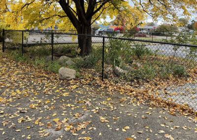 Chain link fence installed with a rock and plant bed along the base in a commercial area