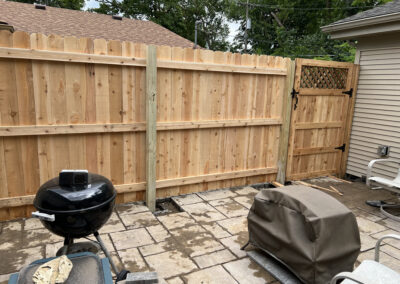 Wooden privacy fence with lattice gate in a backyard setting
