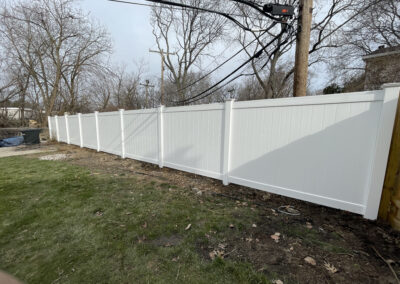 Tall white vinyl privacy fence in an outdoor yard scene