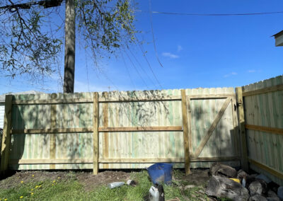 Wooden privacy fence with a gate in a grassy area