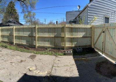 Tall wooden privacy fence with a gate in a residential backyard