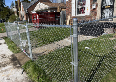 Chain link fence and gate enclosure in front of a brick house