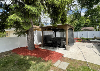 White vinyl privacy fence surrounding a backyard patio with a gazebo and tree