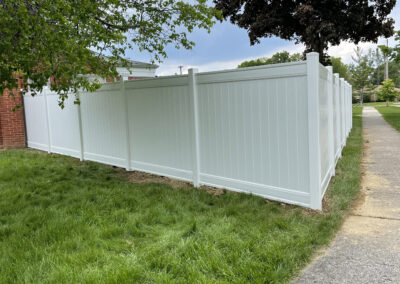 Vinyl privacy fence beside a sidewalk and grassy lawn