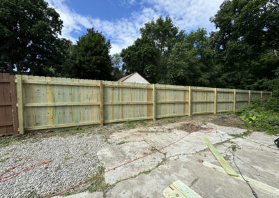 Wooden privacy fence installation with gravel and boards in a residential area