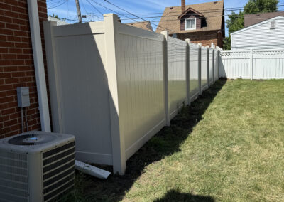 Tall white vinyl privacy fence in a residential backyard