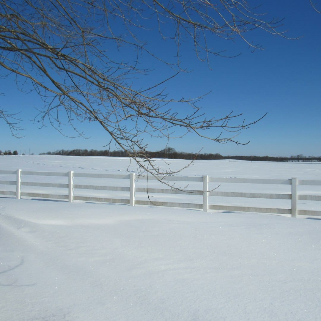 a snow covered field with a white fence
