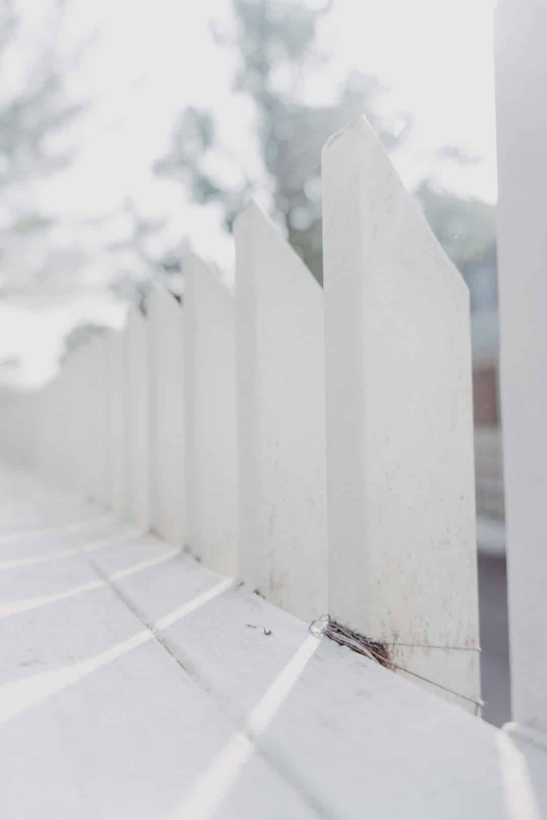 a close up of a white fence with trees in the background